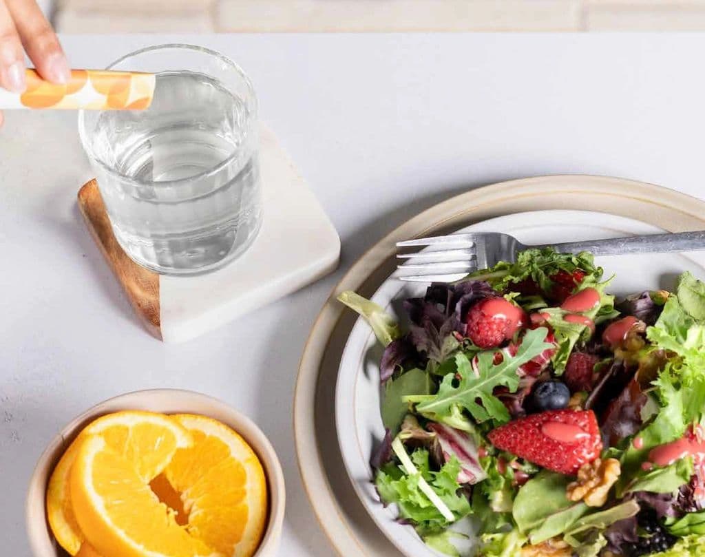 Balance sachet next to a fresh salad and orange